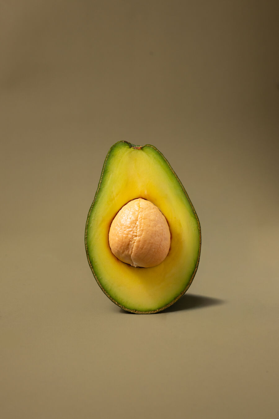 Aguacate Semil 34 partido por la mitad, con el hueso y la pulpa cremosa a la vista, sobre fondo de estudio.